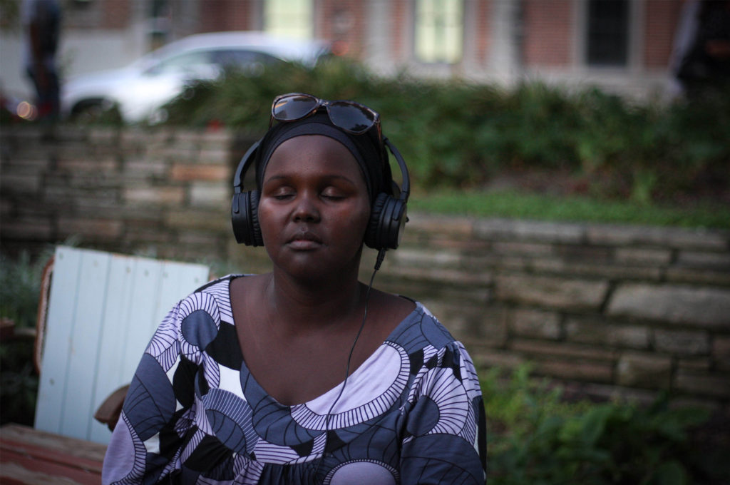A person outside, wearing headphones with their eyes closed, looking peaceful