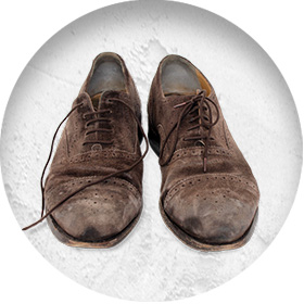 A photo of a pair of well-worn brown suede brogues, with scuffs on the toes