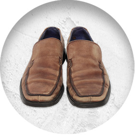 A photo of a pair of lightly worn smart brown leather slip-on shoes.