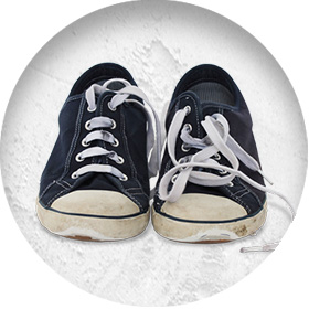 A photo of a pair of blue low-top Converse-style trainers with scuffed toes and white laces.