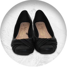 A photo of a pair of black ballet-style pumps.