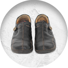 A photo of a pair of lightly worn leather slip-on shoes, with a button on the side and contrast stitching details.
