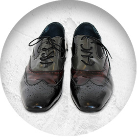 A photo of a pair of smart black patent leather brogues with subtle red and green tones to parts of them.