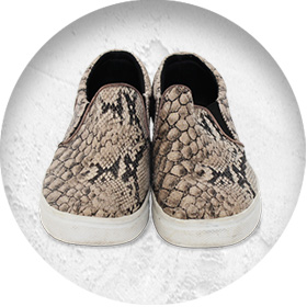 A photo of a pair of slip-on skate shoes with a snake-print pattern.